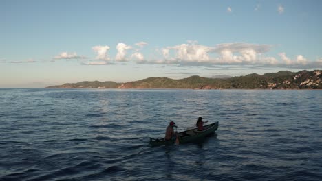 Aerial-drone-shot-follow-couple-canoeing-in-the-middle-of-the-sea