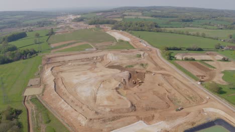 Vista-De-Drones-De-Un-Sitio-De-Construcción-A-Gran-Escala-Dentro-De-Un-Entorno-Rural,-Excavadoras,-Cargadoras-Y-Topadoras