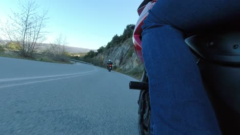 Motorcycle-Riding-on-Twisty-Mountain-Road,-Leaning-Through-Curves,-Side-View-of-Bike-and-Leg