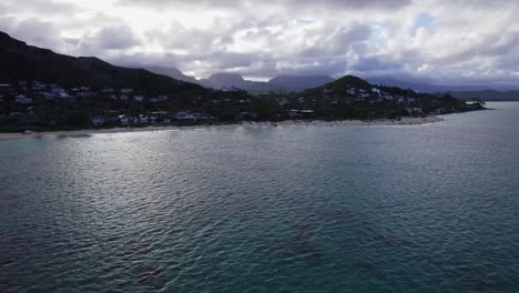 drone-footage-of-Lanikai-beach-showing-coastal-living,-white-sand-beaches-and-water-sports-and-clear-turquoise-water-exposing-the-reefs-on-the-ocean-floor