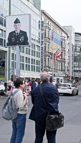 Pareja-De-Turistas-En-El-Checkpoint-Charlie-Berlin,-Punto-De-Referencia-Popular,-Video-Vertical