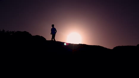 Silhouette-of-a-young-boy-running-from-right-to-left-while-the-sun-is-rising