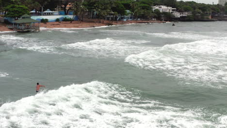 Surfer-surfing-wave-at-Guibia-beach,-Santo-Domingo
