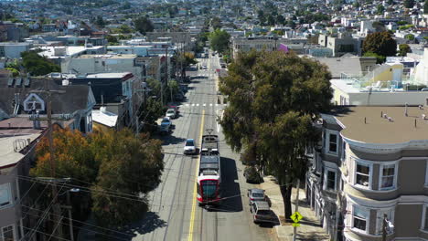 Aerial-view-tracking-a-light-rail-on-the-streets-of-San-Francisco,-California,-USA