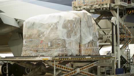 Air-cargo-being-loaded-into-an-aircraft,-featuring-tightly-wrapped-pallets-on-a-conveyor