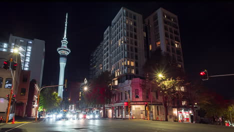 Busy-intersection-in-Auckland,-New-Zealand,-Sky-Tower-in-background,-night-timelapse