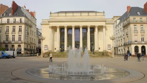 Low-Angle-Shot-Der-Fassade-Des-Graslin-Theaters-Im-Hintergrund-Mit-Brunnen-Im-Vordergrund-Auf-Dem-Graslin-Platz,-Nantes,-Frankreich-Bei-Tag