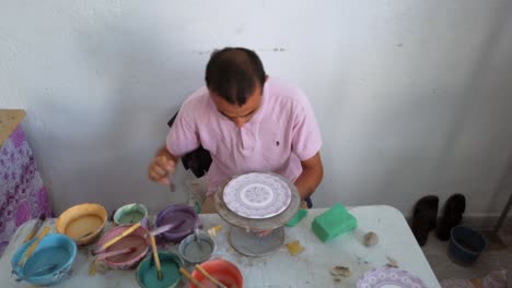 Highly-detailed-clay-dish-painting-with-various-brushes-and-colors,-following-traditional-Arabic-patterns-using-the-wheel-throwing-technique-in-a-Fez-ceramic,-Morocco