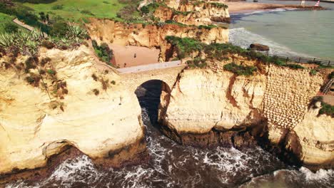 Aerial-4k-drone-descending-view-of-man-made-arch-at-beach-estudantes-in-Lagos,-the-algarve-region-of-Portugal