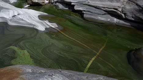 Crystal-clear-blue-water-flows-through-the-old-stones-in-the-Verzasca-valley