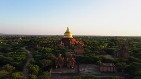 Flug-über-Die-Wunderschöne,-Leuchtend-Goldene-Dhammayazika-Pagode,-Umgeben-Von-üppigen,-Grünen-Bäumen-In-Myanmar-–-Luftaufnahme