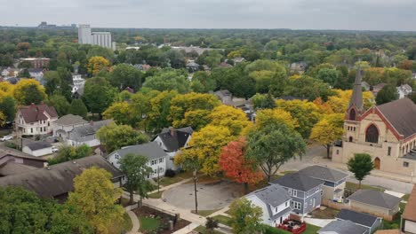 Aerial-drone-view-of-Green-Bay-Wisconsin-autumn-neighborhood-with-church-in-the-foreground-and-Lambeau-Field-in-the-distance,-reveals-grocery-store