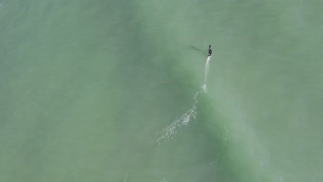 Vista-Aérea-De-Un-Individuo-Montando-Con-Gracia-Olas-Sobre-Su-Tabla-De-Surf,-Encarnando-La-Esencia-Liberadora-Del-Ocio-Y-Las-Actividades-De-Tiempo-Libre-En-Medio-De-La-Vasta-Extensión-Del-Océano.