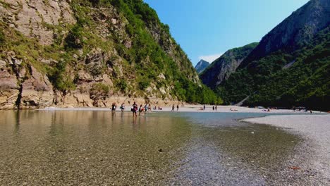 Junge-Leute-Genießen-Das-Paradise-Valley-Mit-Kristallklarem-Flusswasser,-Das-über-Die-Felsigen-Berge-In-Den-Albanischen-Alpen-Fließt