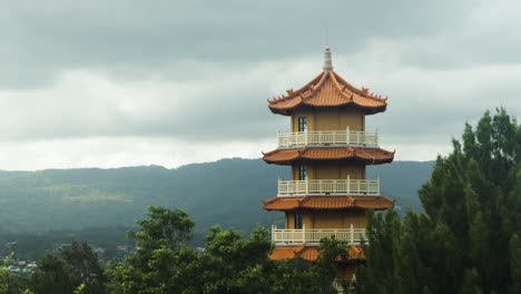 Timelapse-of-Buddist-Temple-Tower-with-mountains-in-background-on-overcast-day