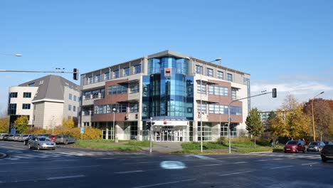 Edificio-Del-Banco-Checo-Komercni-Banka-En-Havirov-Con-Coches-Circulando-Por-El-Cruce-En-Un-Día-Soleado