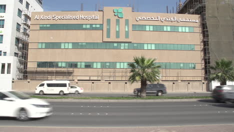 Alkindi-Specialised-Hospital-frontage---streetside-with-cars-crossing-in-the-foreground