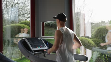 Active-male-do-cardio-training-on-treadmill,-indoor-natural-light-gym