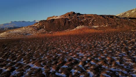 Niedrige-Filmische-Eröffnungssequenz-über-Der-Isländischen-Landschaft-Mit-Luftaufnahme-Einer-Drohne,-Die-Den-Bergigen-Hintergrund-In-Warmem-Sonnenlicht-Enthüllt