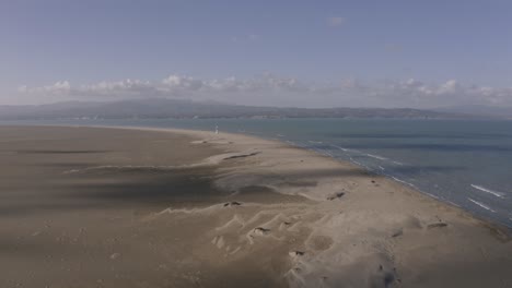 Vista-Aérea-Alta-Y-Amplia-Del-Faro-Del-Delta-Del-Ebro-A-Lo-Lejos-Con-Amplias-Dunas-De-Arena-De-Un-Popular-Lugar-Turístico-En-España