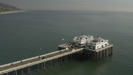 Volando-Sobre-El-Muelle-De-Malibu-Ocupado-Con-Gente-Caminando-Y-Cenando-En-El-Café-Al-Aire-Libre