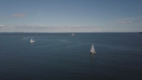 Aerial-Drone-Shot-Flying-Over-Two-Sailboats-In-Rockland-Harbor-In-Maine-Toward-Ocean