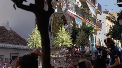 An-editorial-video-of-strong-men-carrying-a-huge-silver-statue-of-the-holy-Maria-at-Rosario-carnival-while-people-let-blossoms-fall-down