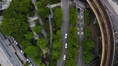 Vista-Aérea-De-Arriba-Hacia-Abajo-De-Las-Calles-Urbanas-Con-Vías-De-Tren-Elevadas-Y-Coches