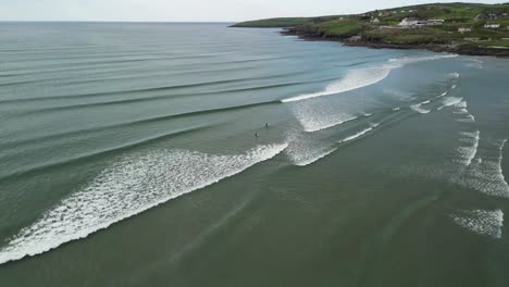 Inchidoney-beach-with-gentle-waves-and-two-surfers-in-water