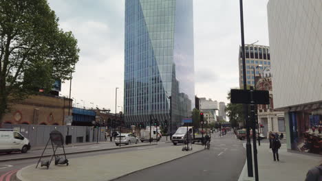 Camera-Tilt,-Green---Blue-Glass-Office-Block-in-London-with-pedestrians-and-traffic