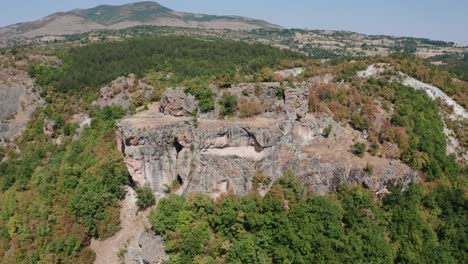 Aerial-View-Of-Thracian-Rock-Tomb-With-Surrounding-Foliage-On-Rhodope-Mountains-In-Bulgaria
