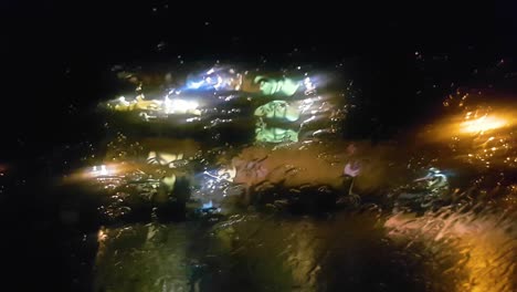 Luces-Brillantes-Para-Ventanas-Y-Máquinas-Bajo-La-Lluvia-En-La-Ventana-Mojada-De-La-Máquina-Por-La-Noche