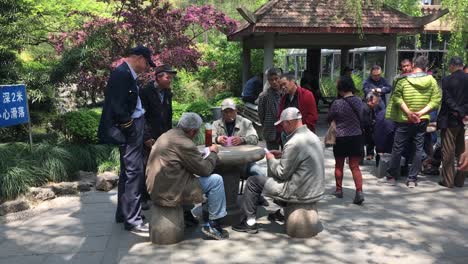 Few-men-playing-and-observing-players-of-Shanghai-rum-card-game-in-Peoples-Square-Park-in-China