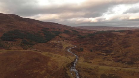 Toma-Aérea-De-Un-Río-En-Las-Tierras-Altas-De-Escocia-En-Hermosos-Colores-Otoñales