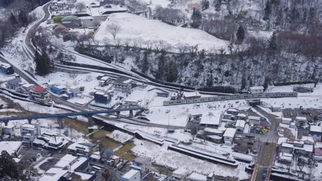 Train-travels-across-Japanese-Countryside-in-the-Winter,-Passing-Yamadera-Temple