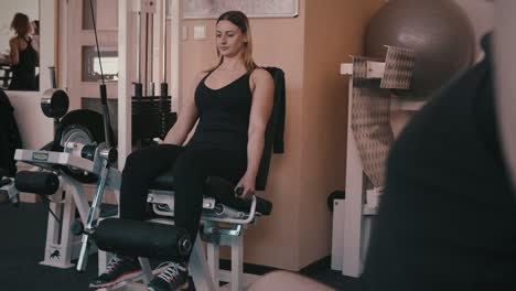 Woman-works-out-in-gym-as-others-work-in-backgroud-and-foreground