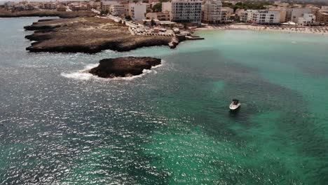 Aerial-descends-to-pleasure-boat-off-Cala-Moreia-beach-on-Mallorca