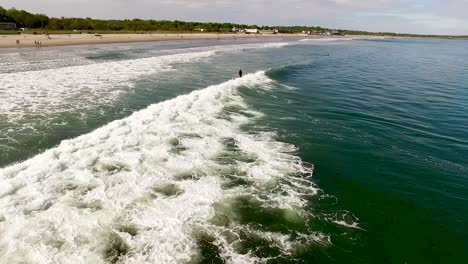 Drohnenaufnahme-Eines-Surfers,-Der-An-Einem-Sommertag-Von-Hinten-Auf-Einer-Welle-Reitet