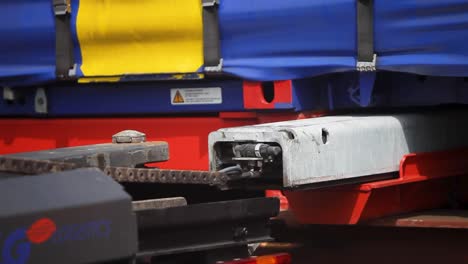 Close-up-of-a-red-train-coupling-mechanism-at-a-railway-station