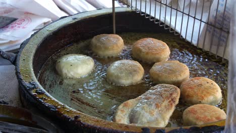 Freshly-made-Chinese-meat-pie-cooking-and-sizzling-on-hot-oil-pan,-pan-frying-until-golden-brown,-close-up-shot-of-popular-Asian-food