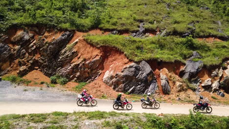 Slow-motion-drone-side-view-of-a-group-of-motorcyclists-riding-along-the-Ma-Pi-Leng-Pass,-Vietnam