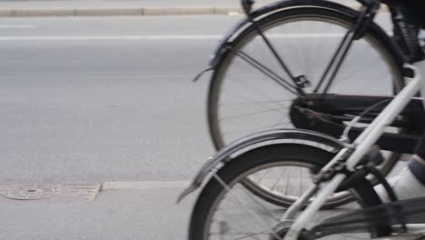 Nahaufnahme-Der-Räder-Von-Fahrrädern-Und-Autos,-Die-In-Kopenhagen,-Nørrebro-Vorbeifahren