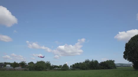 Fleet-of-HSM-Global-delivery-vans-parked-with-airplane-taking-off-behind,-pan