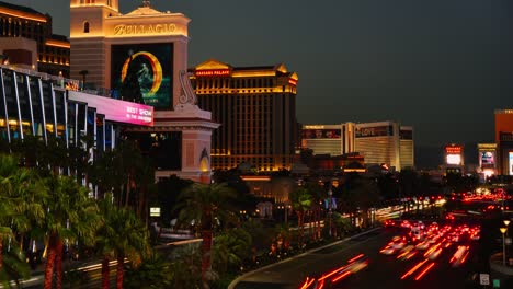 El-Tiempo-De-Puesta-De-Sol-Cae-Sobre-El-Strip-De-Las-Vegas,-El-Tráfico-Del-Bulevar-Con-Una-Visión-General-De-Bellagio,-Ceasars-Palace-Y-Mirage-Hotel-And-Casino.