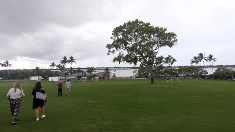 Passersby-strolling-across-green-field-with-picnic-benches