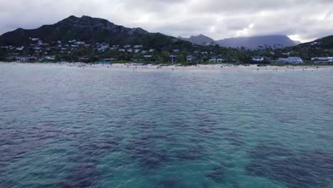 drone-footage-of-Lanakai-Beach-on-the-island-of-Oahu-with-island-mountains-in-the-background-with-white-sand-beaches-lining-the-shore-in-Hawaii