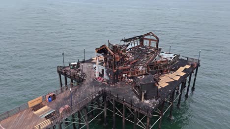 Daños-Por-Incendio-En-El-Muelle-De-Oceanside-El-Antiguo-Restaurante-Ruby&#39;s-Destruido-Drone-Inspeccionando-Los-Daños-Desde-Un-Círculo-Elevado-En-Sentido-Contrario-A-Las-Agujas-Del-Reloj