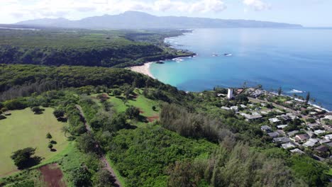 Drone-footage-on-the-North-Shore-of-Oahu-Hawaii-showing-a-180-degree-view-of-the-area-from-the-blue-ocean-water-and-white-sand-beach-and-coastal-villages-to-the-lush-tropical-mountains