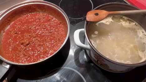 Topf-Mit-Nudeln-Und-Pfanne-Mit-Bolognese-Sauce-Auf-Dem-Herd