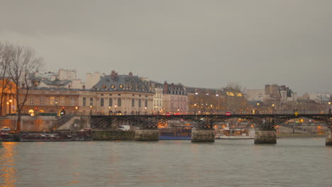 Profile-view-of-Pont-des-Arts-bridge-with-lake-in-foreground-in-Paris,-France-during-sunset